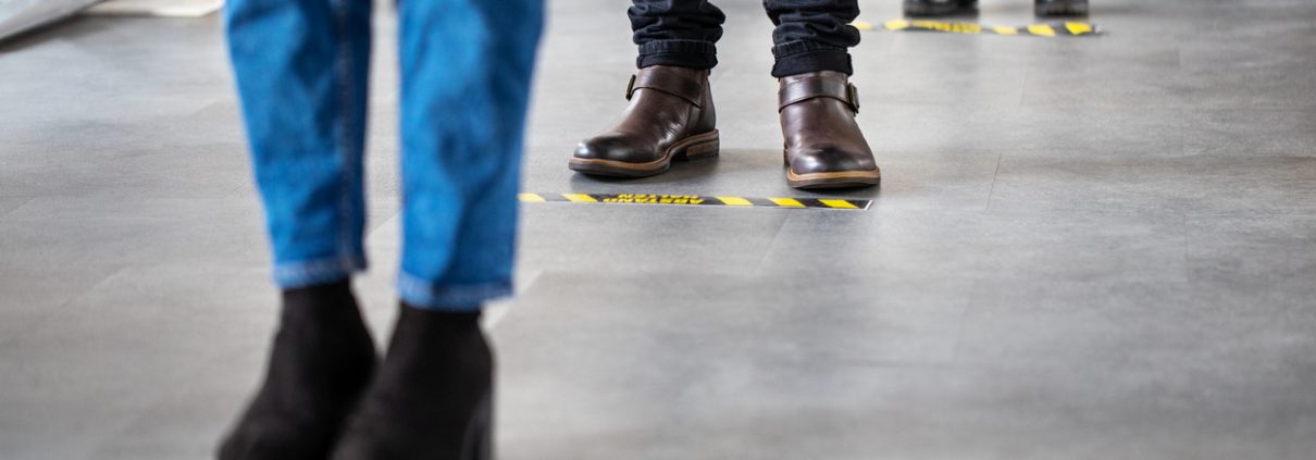 Business people standing behind social distancing signage on office floor