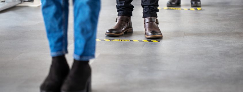 Business people standing behind social distancing signage on office floor